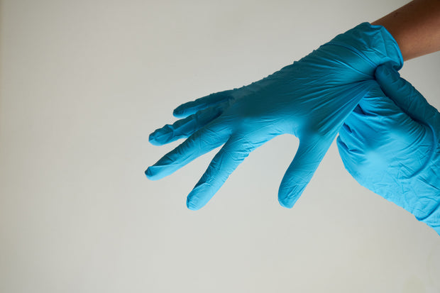 Hände mit blauen Einweghandschuhen